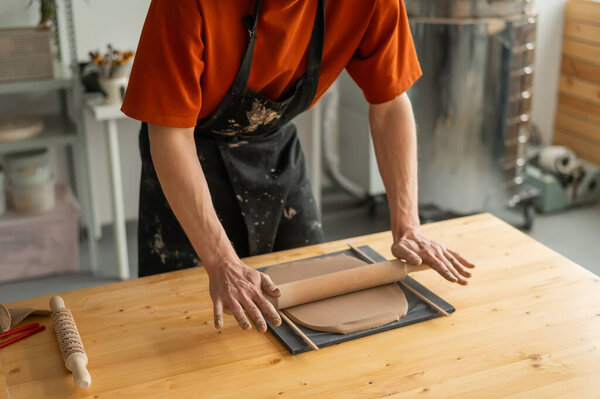 Close-up of potters hands rolling out clay