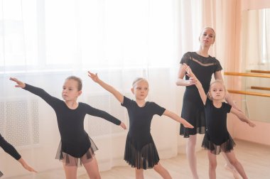 Çocuk bale okulu. Beyaz kadın küçük kızlara bale öğretiyor.