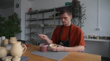 Potter seramik tabakları fırçayla boyar.