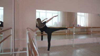 Kafkasyalı sarışın kadın sınıfta bale çalışıyor. Balerin barda prova yapıyor.