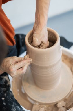 Çömlekçi elleriyle çömlekçi çarkında seramik vazo yaparken. Dikey fotoğraf