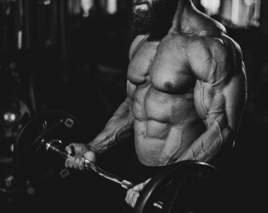 Yüzsüz üstsüz bir adam spor salonunda halterle egzersiz yapıyor. Bicep ağırlıklarla kıvrılır. Tek Renkli