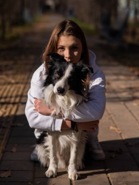 Sonbahar parkında sınır köpeğini kucaklayan beyaz bir kadın. Köpekli bir kızın portresi.