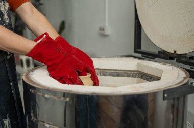 Özel bir fırına seramik yükleyen bir adamın elleri.