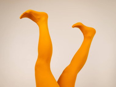 Beyaz arka planda, ocher taytlı kadın bacakları.