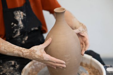 Çömlekçi elleriyle çömlekçi çarkında seramik vazo yaparken.