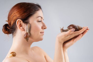 Derisinde salyangoz olan beyaz bir kadının yakın plan portresi. Kozmetolojide kabuklu deniz hayvanı kullanımı