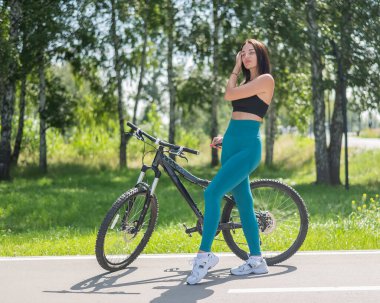 Parkta bisiklet süren beyaz bir kadın.