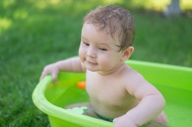 Tatlı erkek bebek yazın havuzda yıkanır.