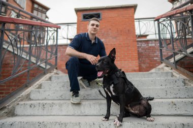 Merdivenlerde pitbull köpeği olan beyaz bir adam oturuyor.