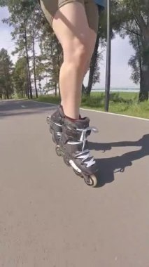 Kadın bacaklarına yakın çekim. Yaz aylarında paten kayan kadınlar. Dikey video