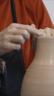 Çömlekçi ellerinin çömlekçi çarkında seramik sürahi yapmasının yakın çekimi. Dikey video