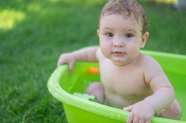 Tatlı erkek bebek yazın havuzda yıkanır.