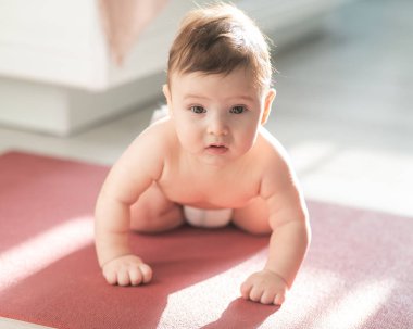 Yerde dört ayak üstünde duran sevimli küçük çocuk.