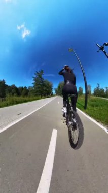 Beyaz bir kadın oturur ve bisiklete biner. Dikey video