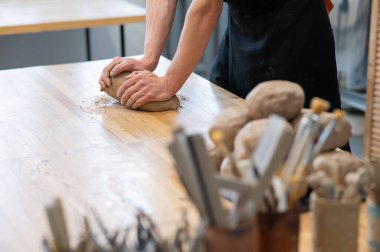 A potter kneads clay before using it in the workshop. Close-up of a mans hands