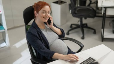 Ofiste cep telefonu kullanan hamile kadın.