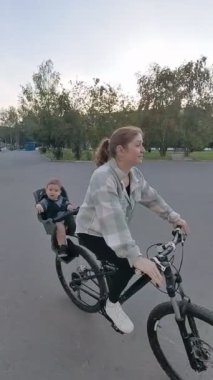 Beyaz kadın oğluyla bisiklete biniyor. Dikey video