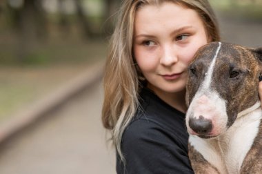 Beyaz kadın portresi açık havada köpeğine sarılıyor.