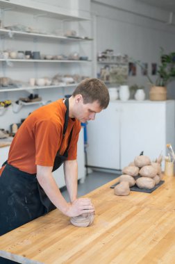 Potter kneads clay before using it in the workshop. Vertical photo