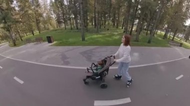 Beyaz kadın bebek arabasıyla küçük oğluyla paten kayıyor.
