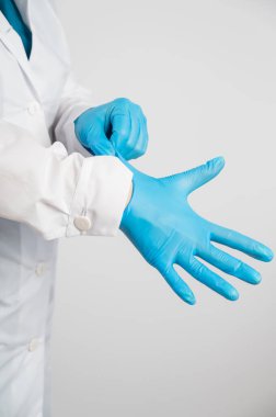Doktor beyaz bir arka plana lateks eldiven takar.