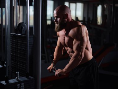 Kel Kafkas vücut geliştirici kabloyla ağır triseps egzersizleri yapıyor.