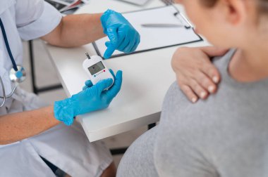 Doktor hamile bir hastanın kan şekerini ölçüyor. Gebelik Diyabet