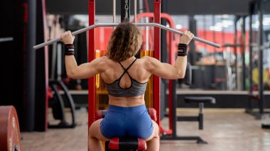 Kırk yaşında, beyaz bir kadının spor salonunda son sürat çekiş yapışının arka görüntüsü.