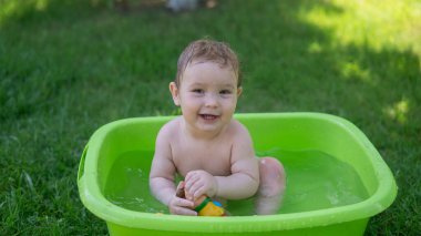 Tatlı erkek bebek yazın havuzda yıkanır.