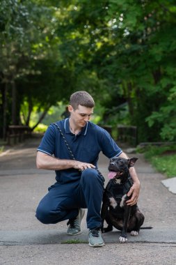 Beyaz bir adam pitbull teriyeri köpeğiyle yürüyor. Dikey fotoğraf