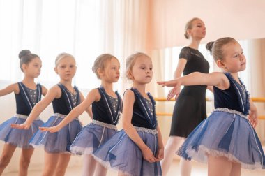 Çocuk bale okulu. Beyaz kadın küçük kızlara bale öğretiyor.