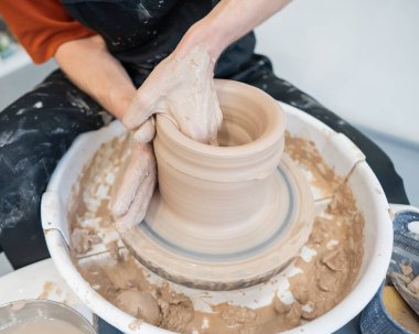 Çömlekçi elleriyle çömlekçi çarkında seramik vazo yaparken.