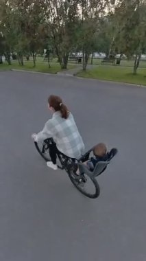 Beyaz kadın oğluyla bisiklete biniyor. Dikey video
