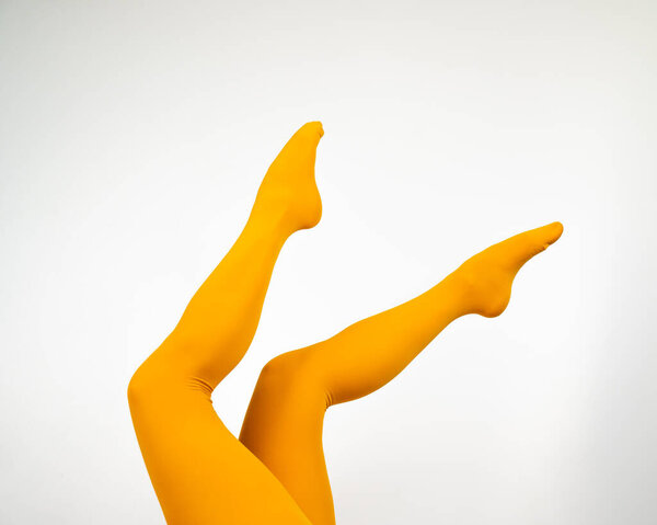 Female legs in ocher tights on a white background