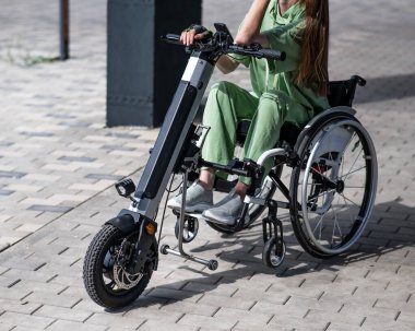 Tekerlekli sandalyeyi özel bir elle kontrol eden bir kadın. Elektrikli motosiklet kullanan kadınların yakın plan fotoğrafları.