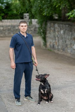 Beyaz bir adam pitbull teriyeri köpeğiyle yürüyor. Dikey fotoğraf