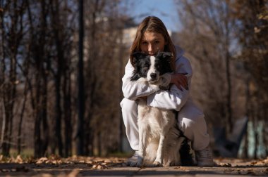 Sonbahar parkında sınır köpeğini kucaklayan beyaz bir kadın. Köpekli bir kızın portresi.