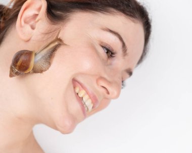 Güzel beyaz bir kadın yalan söylüyor ve salyangozlar yüzünde sürünüyor. Cilt bakımı ve yaşlanmayı önleme.