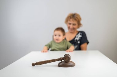 Yaşlı bir kadın jürinin arkasında bir çocuk tutuyor.