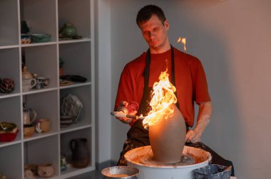 Çömlekçinin biri çömlekçi çarkında gaz yakan bir sürahi yakıyor.