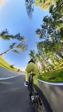 Bisiklet süren, geniş kalçalı, beyaz bir kadının arka görüntüsü. Dikey video 360