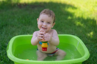 Tatlı erkek bebek yazın havuzda yıkanır.