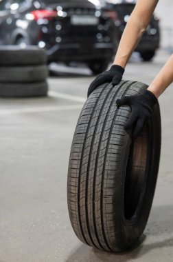 Eski araba lastiği tutan adam. Tekerlekli mekanik elleri kapat