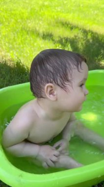 Yazın dışarıdaki havuzda şirin bebek banyosu yapıyor. Dikey video