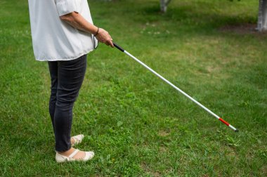 Yaşlı bir kadının, parkta yürürken değnek değneği kullanan bacaklarını yakın plan.