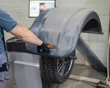 Tamirci atölyede tekerleği dengeliyor.