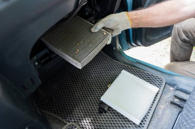 Bir tamirci arabanın kabin hava filtresini değiştirir.