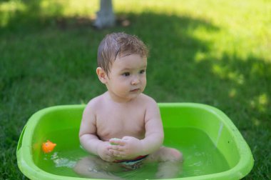 Tatlı erkek bebek yazın havuzda yıkanır.