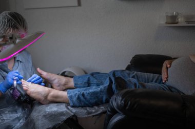 Güzellik salonunda hırdavat pedikür yapan hamile bir kadın.